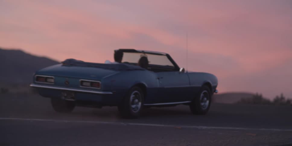 A man and woman are driving in a car at dusk
