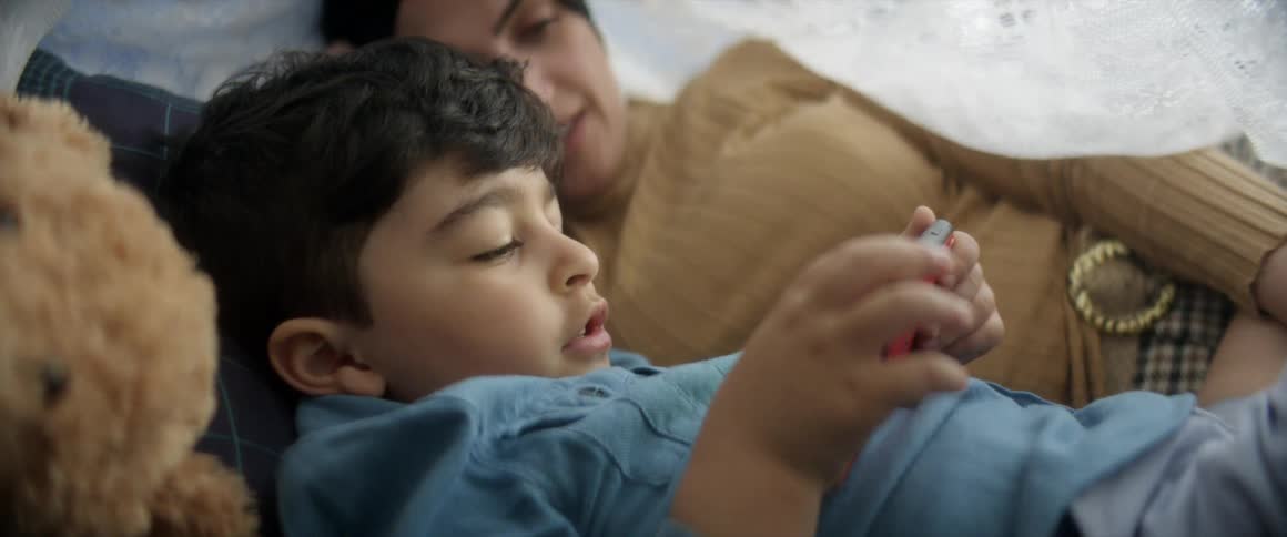 Mother and son lying watching something on smartphone