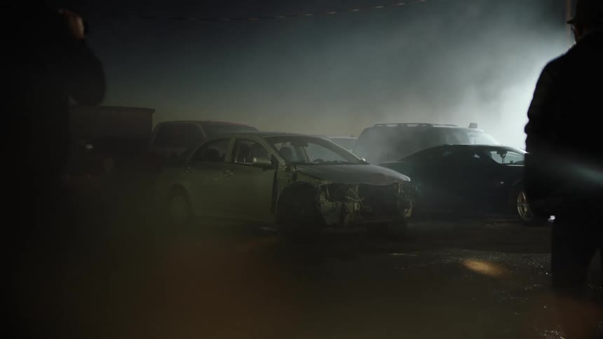 A group of men walk through the junkyard