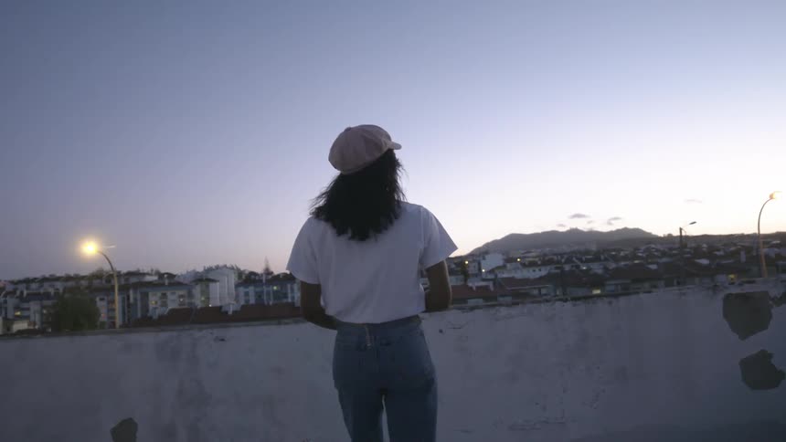 A person is walking in a downtown city at dusk