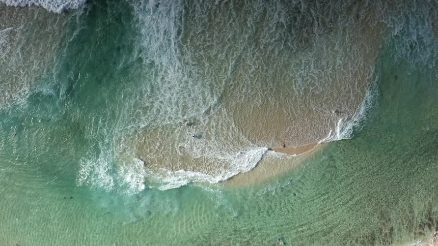 People standing on a beach with sand and waves