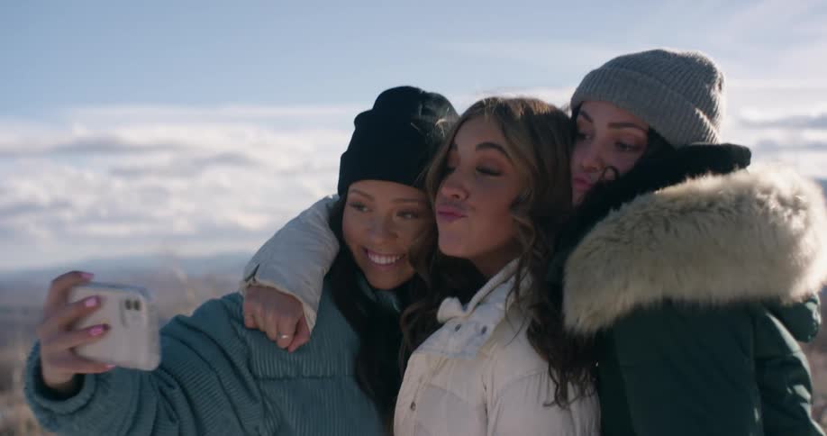 Three friends are outdoors taking a selfie together