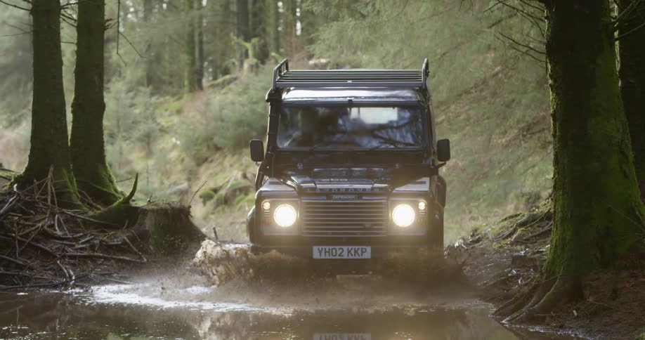 An off road vehicle driving on a flooded trail in the forest