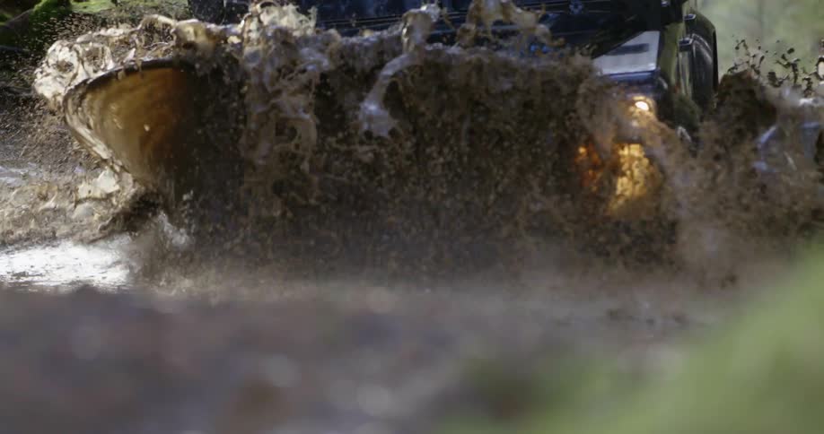 A vehicle driving on a dirt road with water and mud
