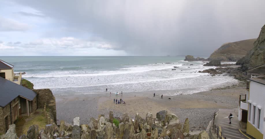 People walking on a beach between a small town and a cove