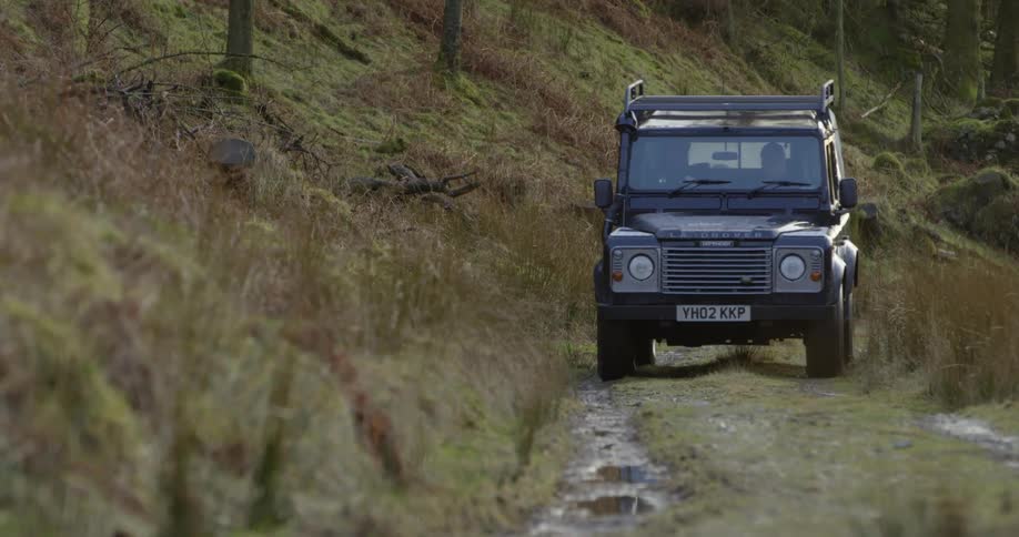 Two people drive a vehicle off road in a forest area