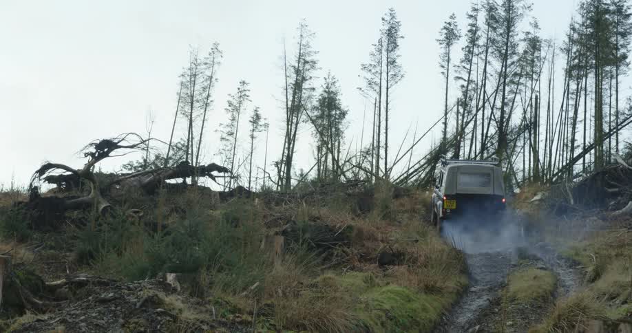 An off road vehicle climbing a steep hill near the broken treeline