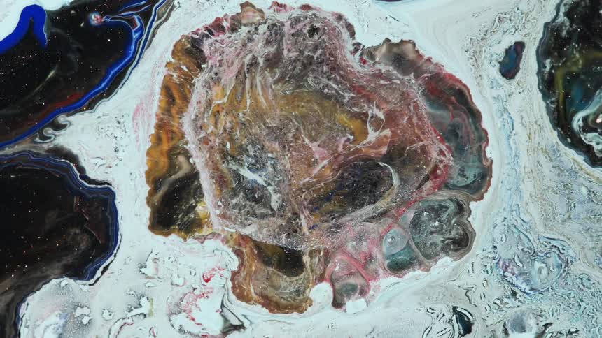 Pink and orange liquids with a separate blue liquid outline splotch under a microscope move outwards in a white liquid