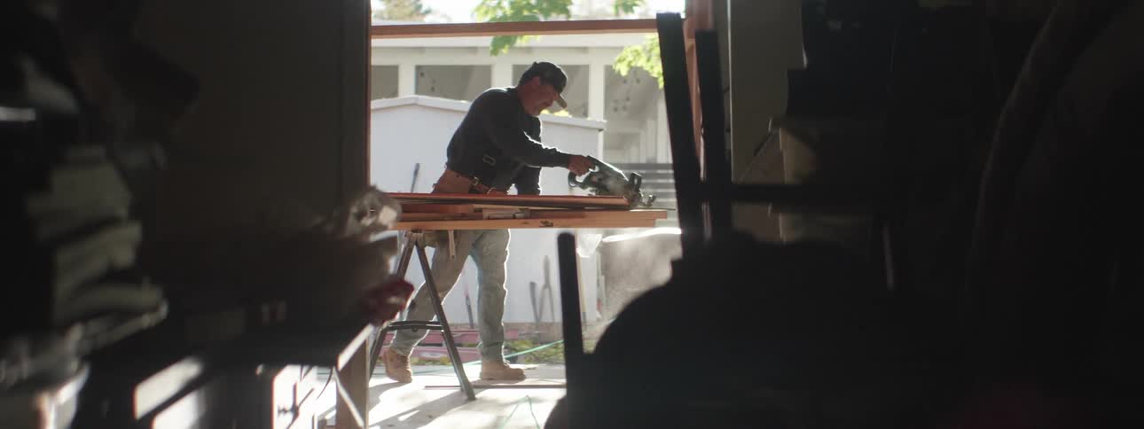 Carpenter sawing off wood with a power saw at a job site