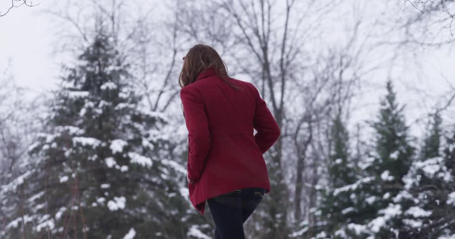A woman wearing a red coat walking on a snowy winter day