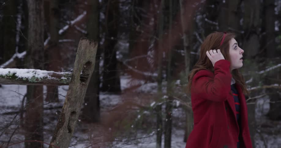 A woman wearing a red jacket walks in the snow