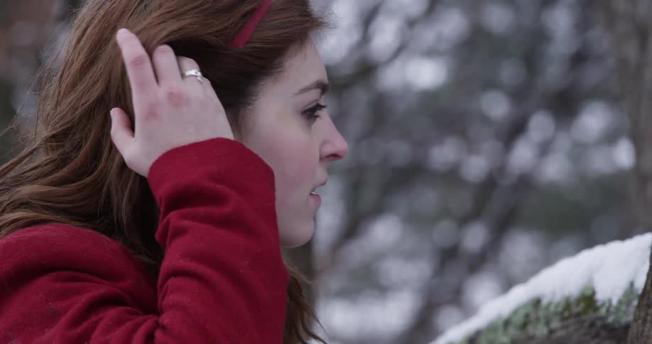 A woman in a red coat looks up into the air