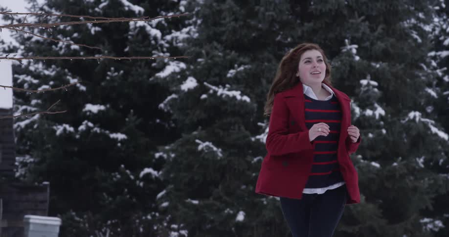 A woman runs happily through a snow-covered landscape