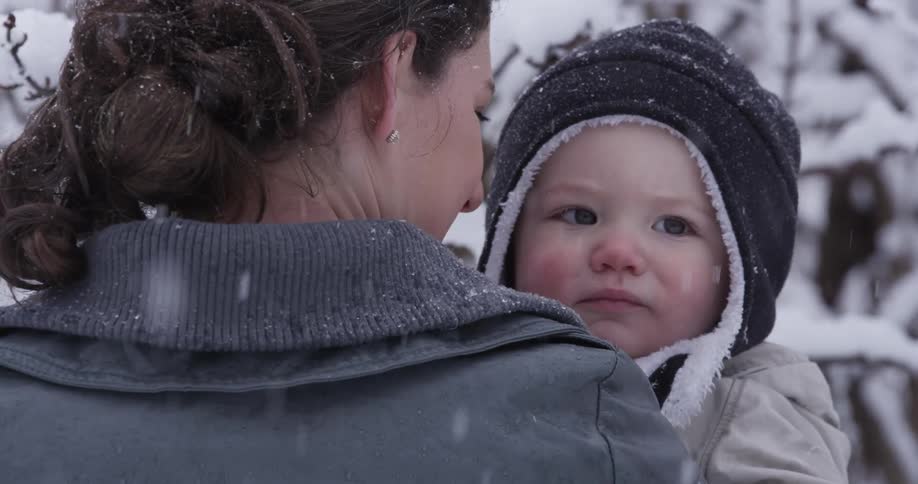 A woman and child stand outside in the snow