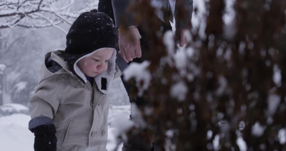 A child is walking with a parent as it snows