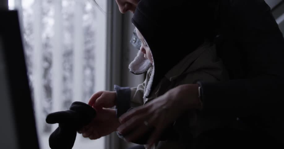 A woman helps a child put on winter gloves