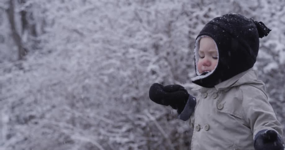 A toddler walks as snow falls