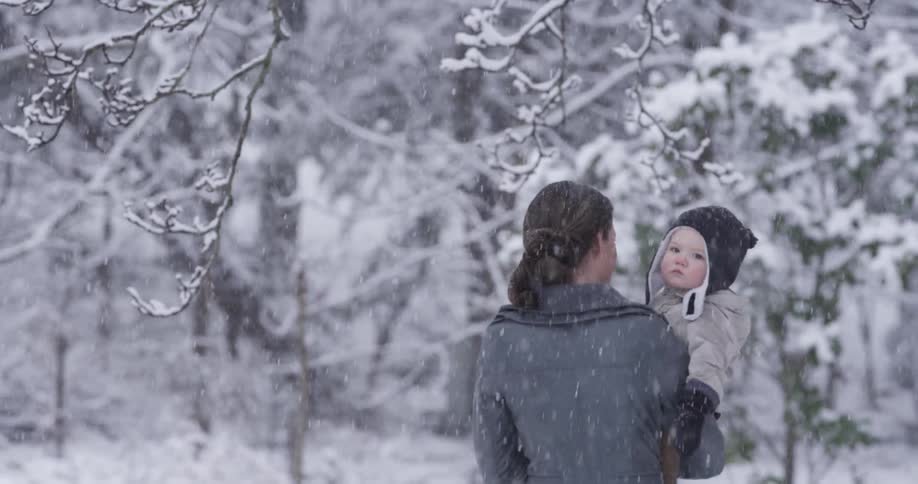 A woman walks with her child in the snow