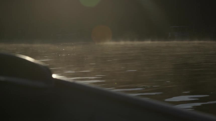 View of water from the side of a boat as the sun shines down