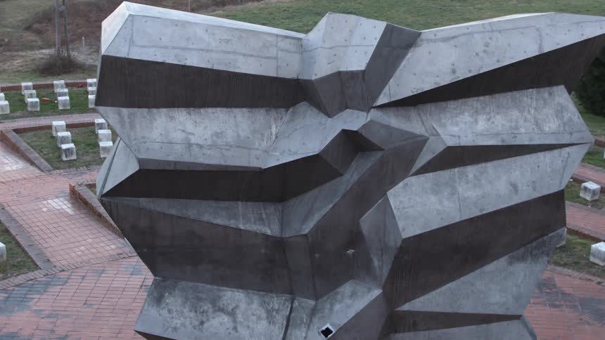 A sculpture in a park with grass and trees in the background