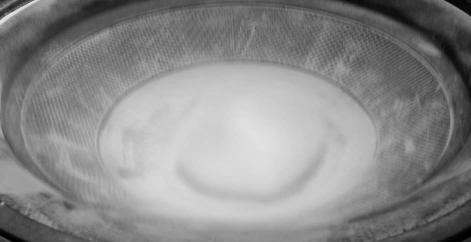 White powder vibrating and moving outwards on a black speaker