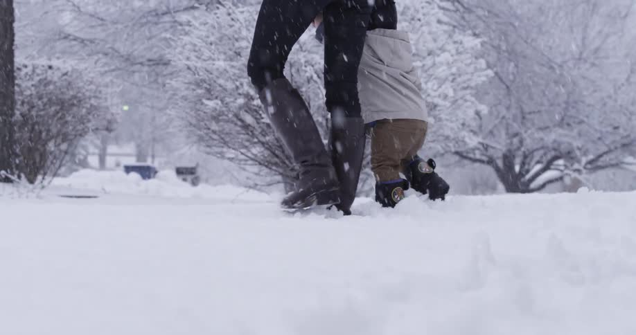 A woman walks her small child through the snow