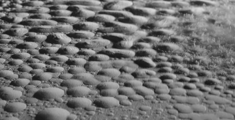 Drops of water covered in white dust vibrating over a surface