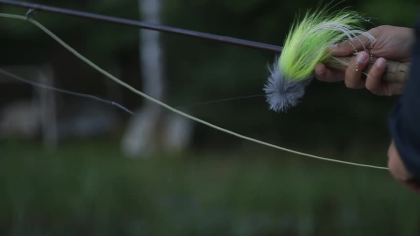 A man is attaching a lure to a fishing pole