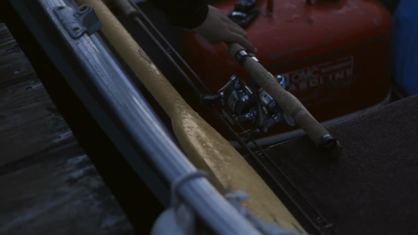 A person places two fishing rods in a boat