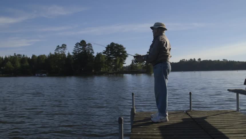 An old man standing on a dock fishing