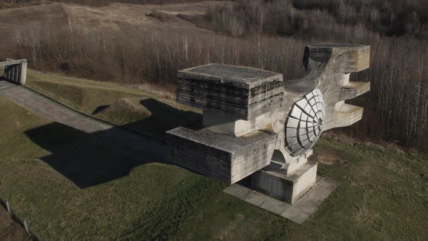 A wooden sculpture sits on a grassland above a forest