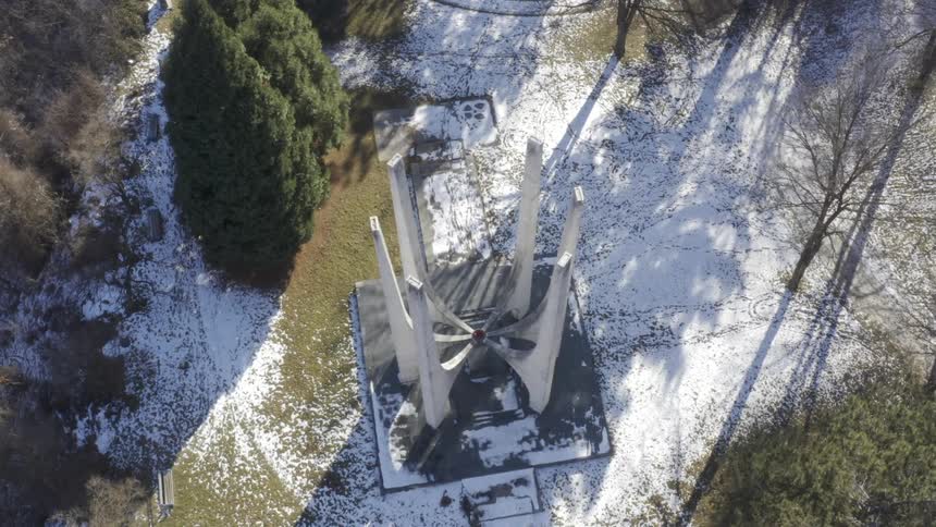 Metal sculpture stands on platform in middle of snow covered park