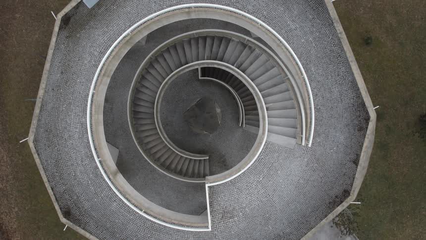A spiral staircase leading to the top of a tower in a field during the day