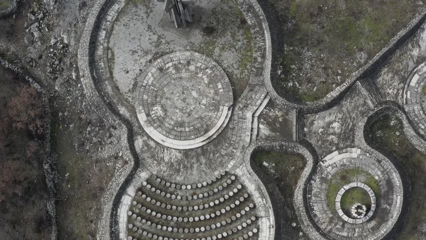 A monument and a sculpture made of concrete surrounded by rocks and grass