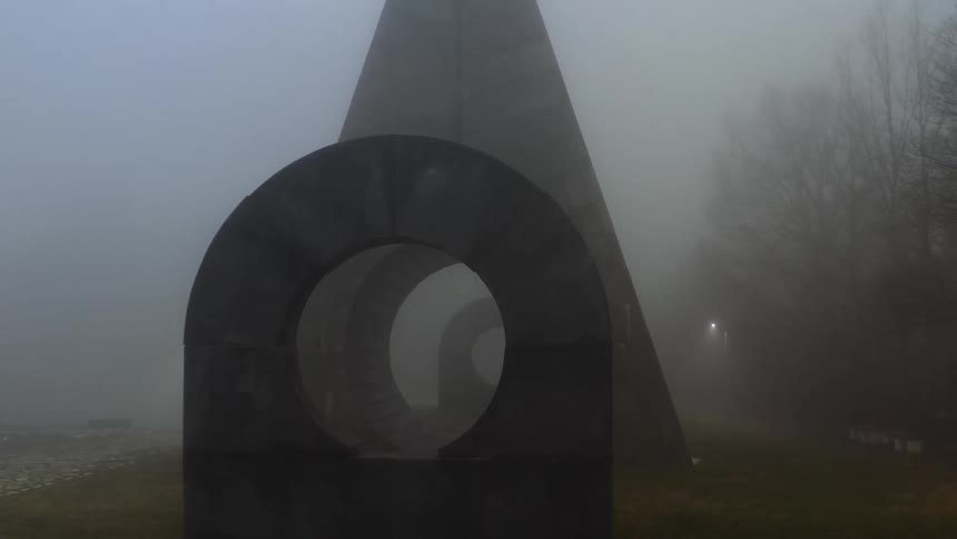 Geometrical hollow concrete sculptures standing in the mist on a park