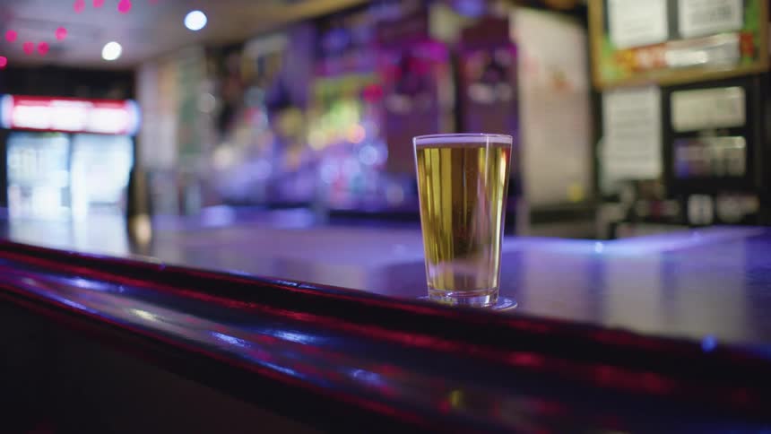 Full glass of beer on counter at a pub under spinning lights