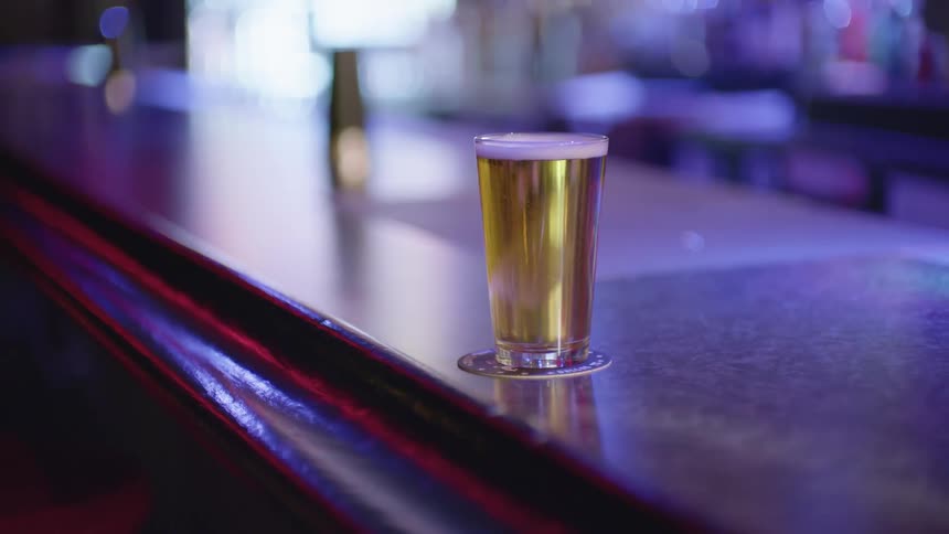 Beer glass on a bar counter under spinning lights