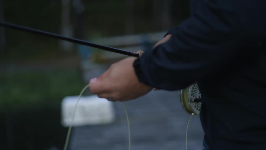 A man's hands spool out line from a fishing reel