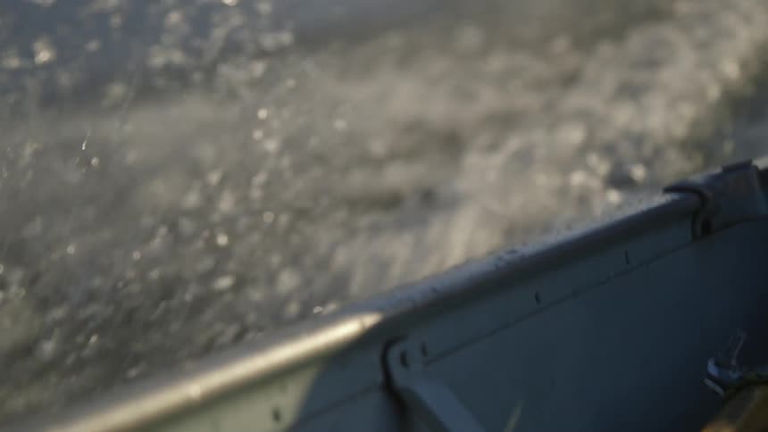 The side of a boat as it moves through the water in the day