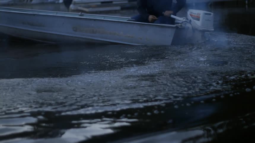 A man on a small boat takes off across a lake