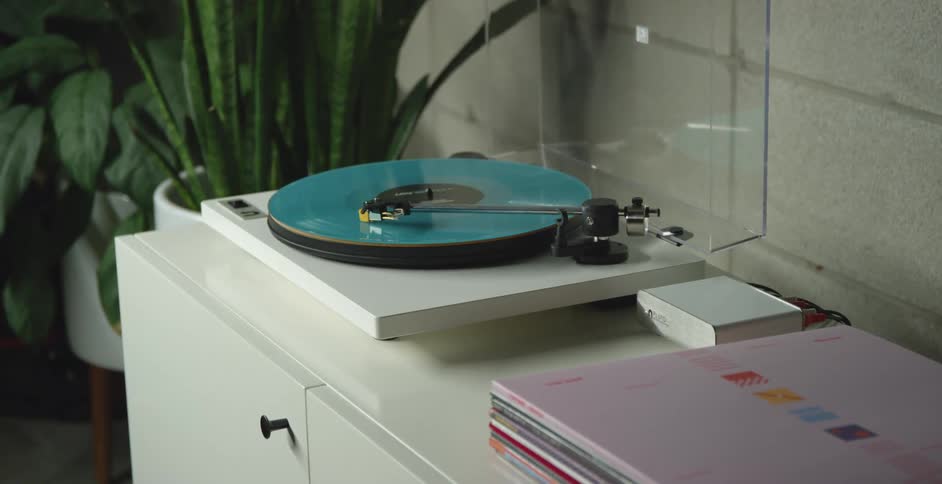 Record albums sit next to playing record player