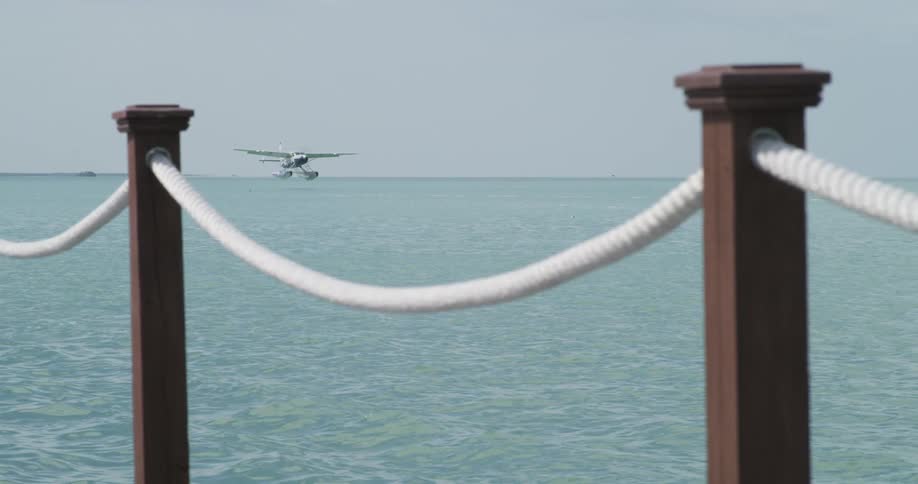 Seaplane flies low over rippling ocean near shore