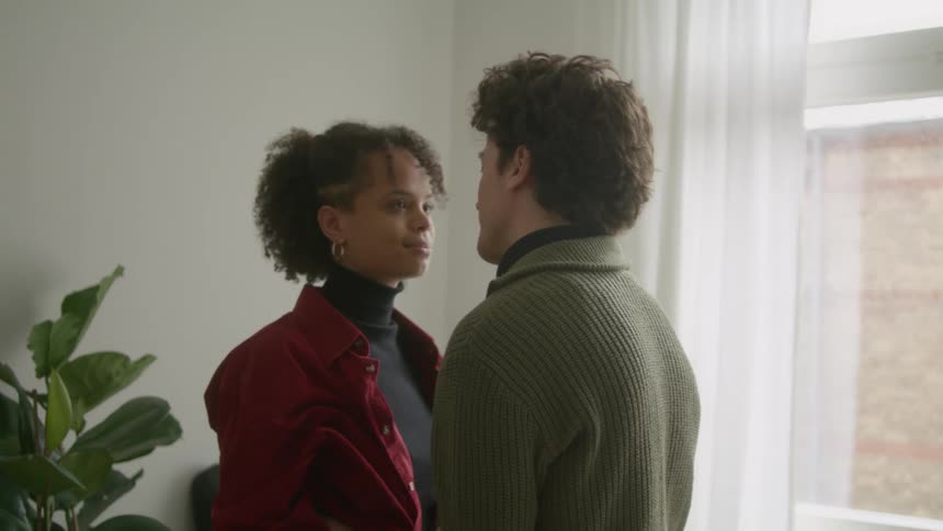 Couple hug and sway near curtained window