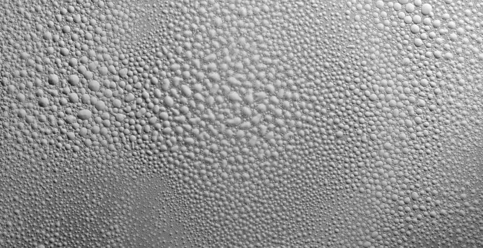 Drops of water covered in white dust move and shatter over a vibrating surface