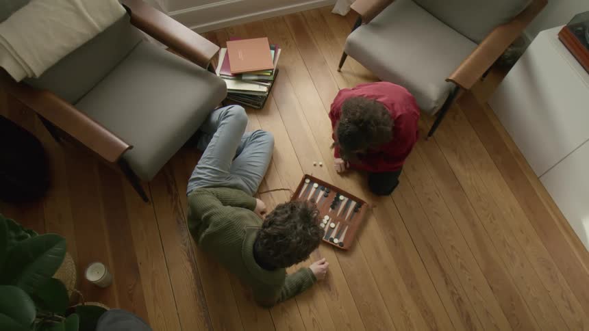 Man and woman play backgammon on the floor in the living room