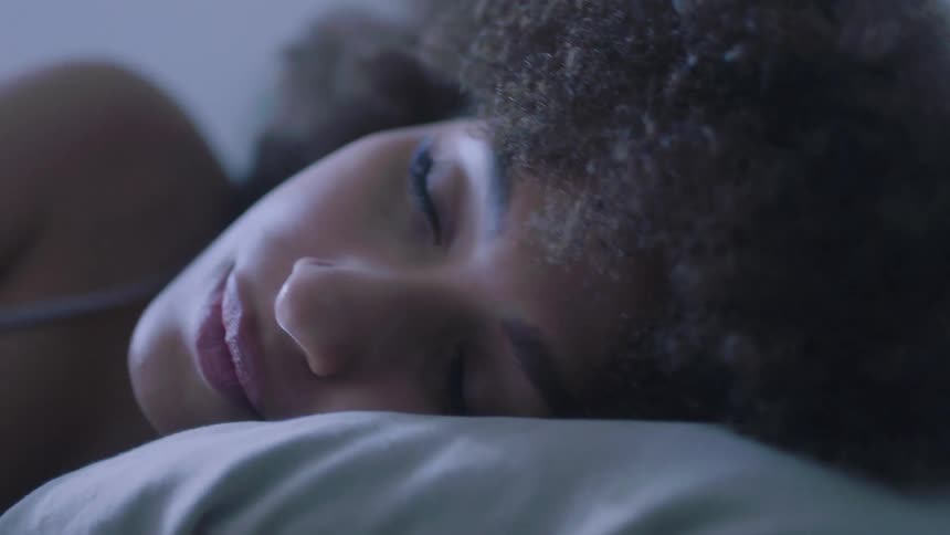 Brunette woman with frizzy hair sleeps in bed peacefully