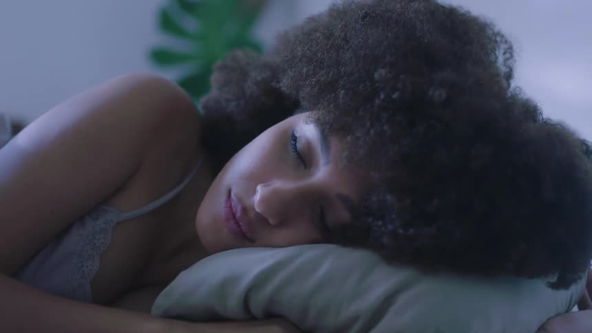 Young woman with an afro sleeping on a bed in the bedroom