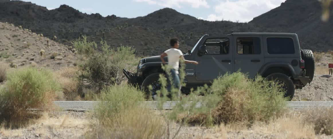 Young woma ends a call on her smartphone and boards a car parked on the road near the mountains