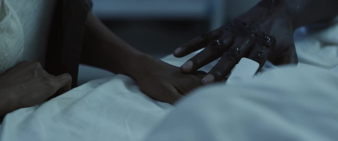 A man in a hospital bed holding a womans hand