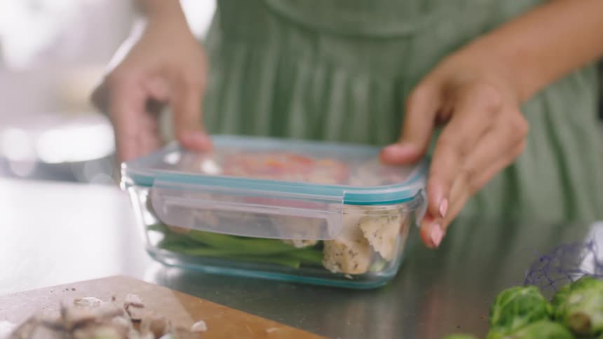 Woman packs food into containers stacking them on counter